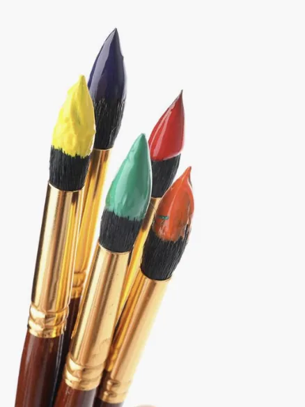 Vibrant paint-dipped brushes on white background
